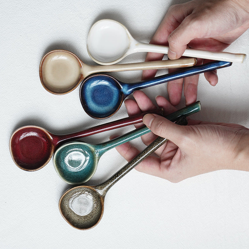 Colorful ceramic spoons held by hands on a light background